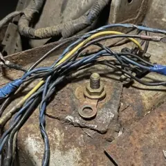 Faisceau de fils de voiture rouillé, un symptôme de mauvaise masse. Connexions électriques bricolées sur une surface corrodée.