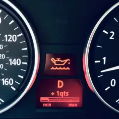 Tableau de bord d'une voiture avec le symbole vidange voiture allumé, indiquant un niveau d'huile bas.