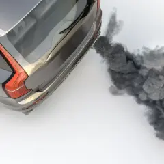 Une voiture qui fume noir à l'accélération diesel, libérant un nuage épais.