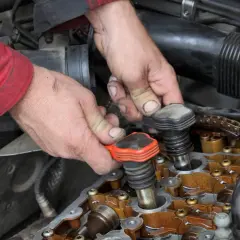 Mains d'un mécanicien retirant une bobine d'allumage. Faut-il changer les 4 bobines d'allumage ?
