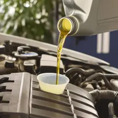 Vidange 208 essence : de l'huile neuve est versée dans un petit récipient sur le moteur d'une voiture.