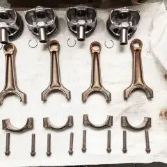 Pièces d'un moteur : pistons, bielles, chapeaux de bielle et vis. Prêt à réparer un moteur qui a eu un problème de couler une bielle.