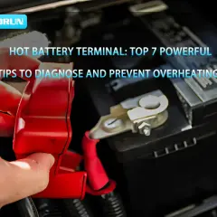 Main d'une personne tenant un cache rouge sur une borne de batterie de voiture, suggérant une batterie qui chauffe. Conseils pour diagnostiquer et prévenir la surchauffe.
