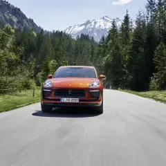 Porsche Macan orange sur une route de montagne, respectant la norme européenne d'émissions.