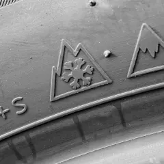 Gros plan sur un pneu avec les marquages "M+S" et le symbole 3PMSF (flocon dans une montagne), indiquant sa capacité à affronter la neige.