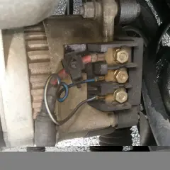 Vue rapprochée du régulateur d'alternateur avec ses connexions électriques.
