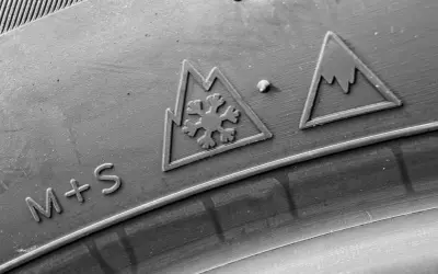 Gros plan sur un pneu avec les marquages "M+S" et le symbole 3PMSF (flocon dans une montagne), indiquant sa capacité à affronter la neige.