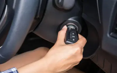 Main tenant insère la clé dans le contact, espérant que la voiture qui ne démarre pas finira par démarrer.