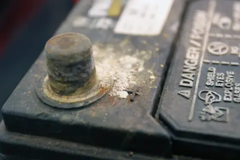 Oxydation sur une cosse de batterie, expliquant pourquoi les cosses de batterie s'oxydent. Danger : gaz explosifs.
