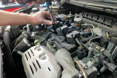 Mécanicien remplaçant une bougie d'allumage pour optimiser la durée de vie de la bougie d'allumage. Moteur de voiture détaillé.