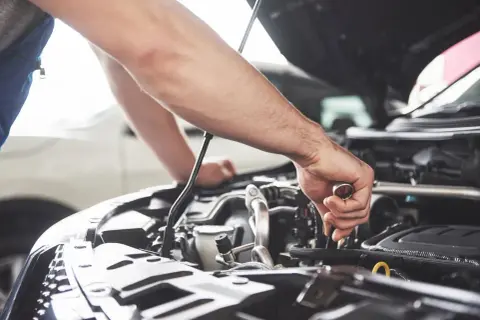 Un mécanicien effectue l'entretien de la voiture, serrant une pièce du moteur avec une clé.