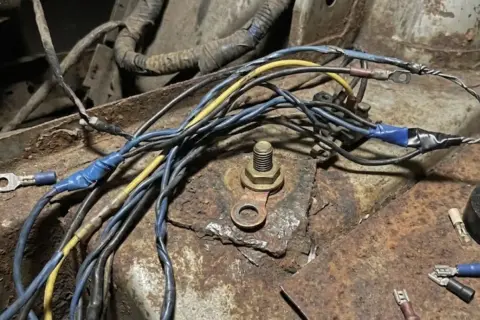 Faisceau de fils de voiture rouillé, un symptôme de mauvaise masse. Connexions électriques bricolées sur une surface corrodée.