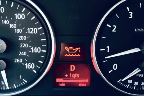 Tableau de bord d'une voiture avec le symbole vidange voiture allumé, indiquant un niveau d'huile bas.