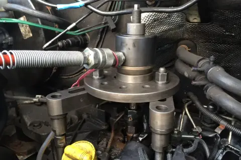 Outil pour comment enlever un injecteur grippé sans extracteur. Le dispositif est fixé sur le moteur, prêt à extraire l'injecteur récalcitrant.