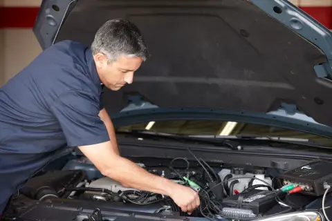 Mécanicien diagnostiquant un démarrage difficile à chaud diesel. Il utilise un appareil de mesure connecté au moteur.