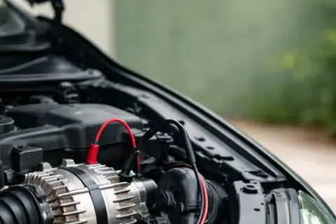 Diagnostic d'un panne alternateur symptôme : un alternateur de voiture avec des câbles de test connectés.