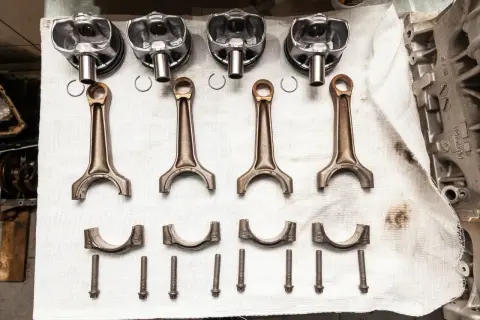 Pièces d'un moteur : pistons, bielles, chapeaux de bielle et vis. Prêt à réparer un moteur qui a eu un problème de couler une bielle.