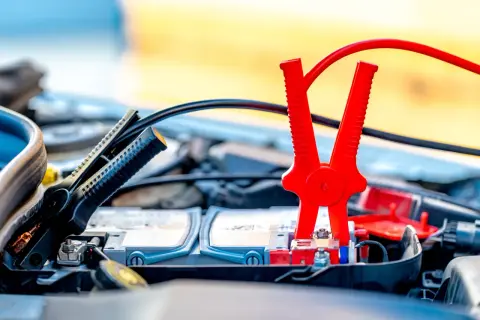 Pinces rouges et noires connectées à la batterie pour démarrer une voiture essence ou diesel.