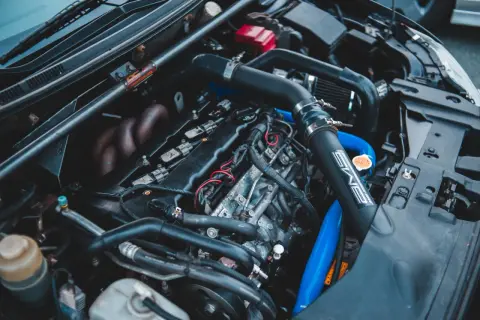 Moteur de voiture avec durites bleues et noires. On peut tester l'actuateur de ralenti sur ce moteur.