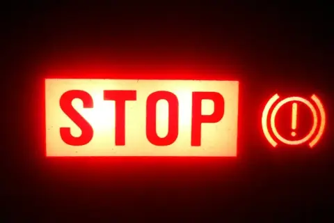 Voyant rouge "STOP" allumé, avec le symbole du frein à main activé.