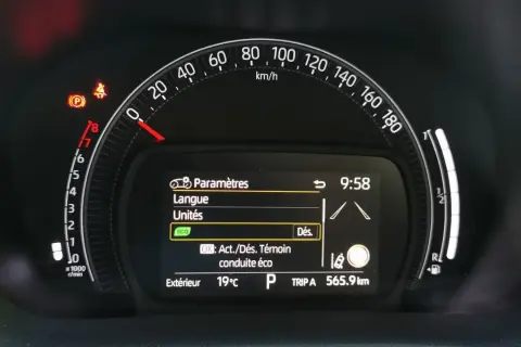 Tableau de bord Toyota Aygo X : voyant pression pneu allumé, menu paramètres affiché. Vitesse 0 km/h, température extérieure 19°C.