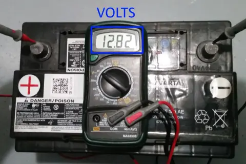 Comment tester une batterie : un multimètre affiche 12,82 V sur une batterie de voiture Varta.