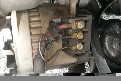 Vue rapprochée du régulateur d'alternateur avec ses connexions électriques.