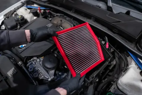 Maintenant, je vais nettoyer le filtre à air de la voiture. Il est rouge et rectangulaire.