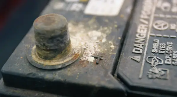 Oxydation sur une cosse de batterie, expliquant pourquoi les cosses de batterie s'oxydent. Danger : gaz explosifs.