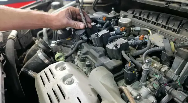 Mécanicien remplaçant une bougie d'allumage pour optimiser la durée de vie de la bougie d'allumage. Moteur de voiture détaillé.