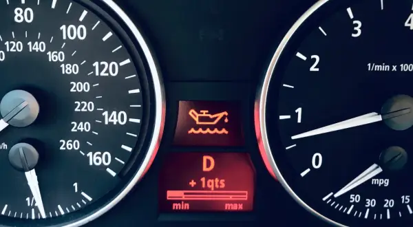 Tableau de bord d'une voiture avec le symbole vidange voiture allumé, indiquant un niveau d'huile bas.