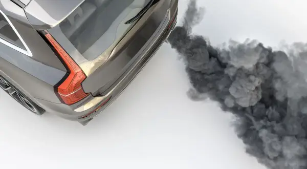 Une voiture qui fume noir à l'accélération diesel, libérant un nuage épais.