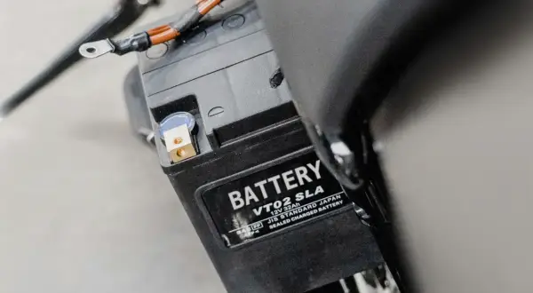 Batterie de moto, peut-être un symptôme de démarreur fatigué. Les câbles sont connectés aux bornes.