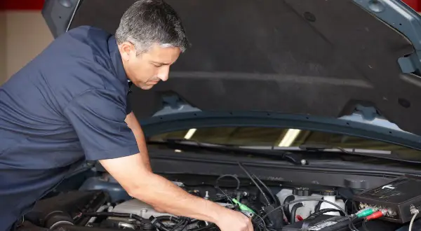 Mécanicien diagnostiquant un démarrage difficile à chaud diesel. Il utilise un appareil de mesure connecté au moteur.