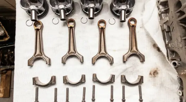 Pièces d'un moteur : pistons, bielles, chapeaux de bielle et vis. Prêt à réparer un moteur qui a eu un problème de couler une bielle.