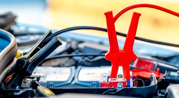 Pinces rouges et noires connectées à la batterie pour démarrer une voiture essence ou diesel.