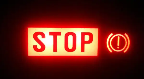 Voyant rouge "STOP" allumé, avec le symbole du frein à main activé.