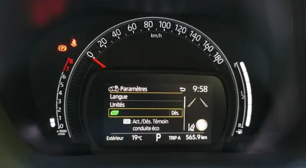 Tableau de bord Toyota Aygo X : voyant pression pneu allumé, menu paramètres affiché. Vitesse 0 km/h, température extérieure 19°C.