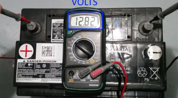 Comment tester une batterie : un multimètre affiche 12,82 V sur une batterie de voiture Varta.