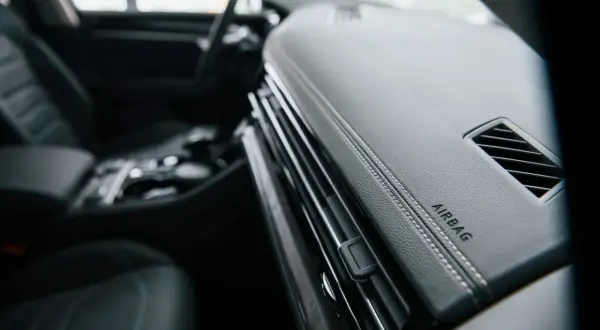 Vue intérieure d'un Peugeot Expert. Le tableau de bord en cuir noir avec surpiqûres blanches et l'inscription "AIRBAG" sont visibles. L'emplacement du calculateur airbag est ici.