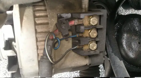 Vue rapprochée du régulateur d'alternateur avec ses connexions électriques.