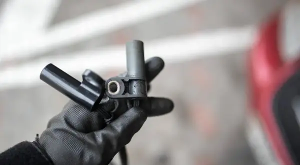 Main tenue un capteur d'arbre à cames pour un moteur 1.5 dCi. Ce composant est essentiel pour le bon fonctionnement du moteur.