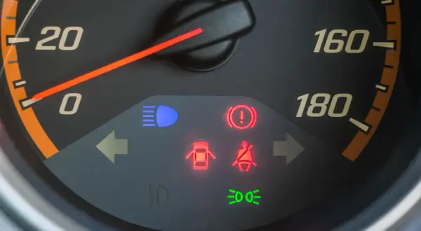 Tableau de bord avec voyant rouge de pression pneu allumé, signalant un problème.