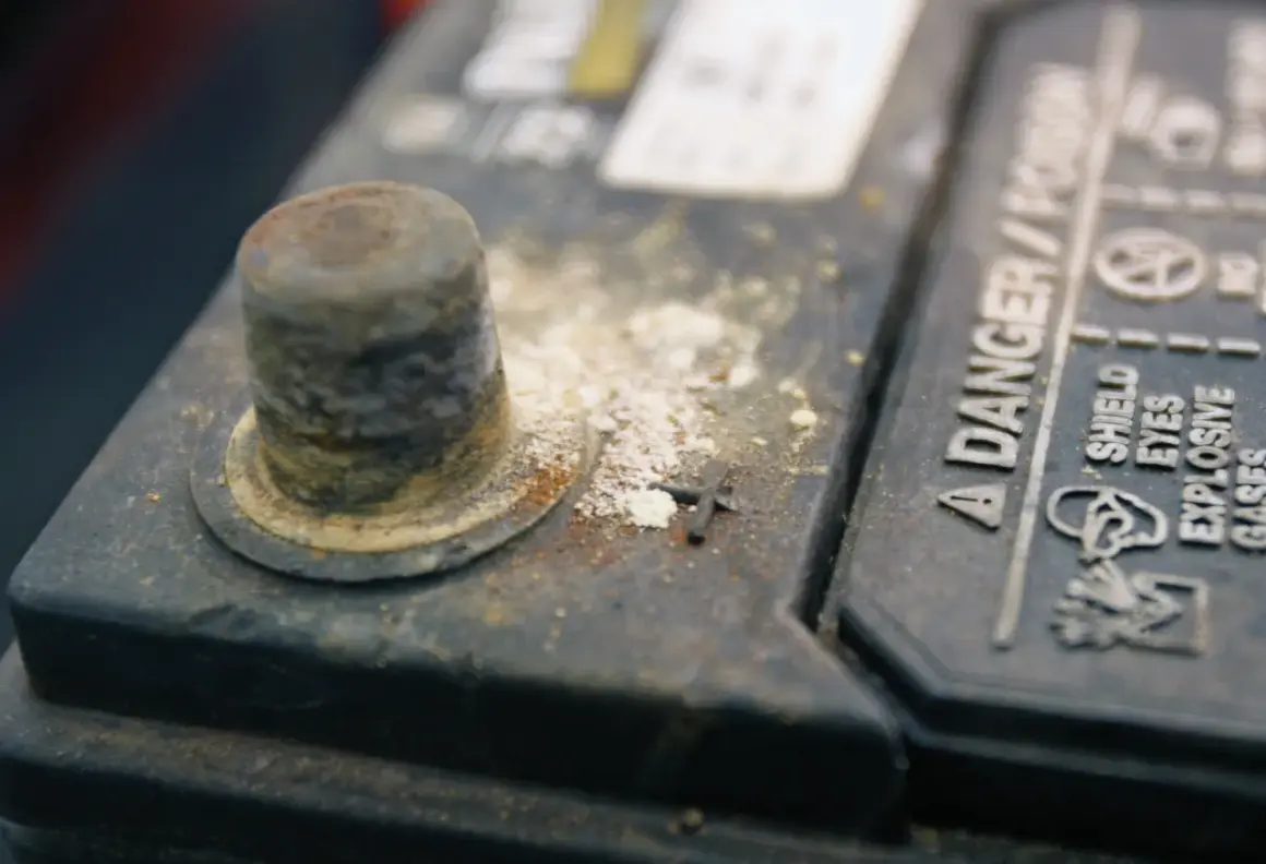 Oxydation sur une cosse de batterie, expliquant pourquoi les cosses de batterie s'oxydent. Danger : gaz explosifs.