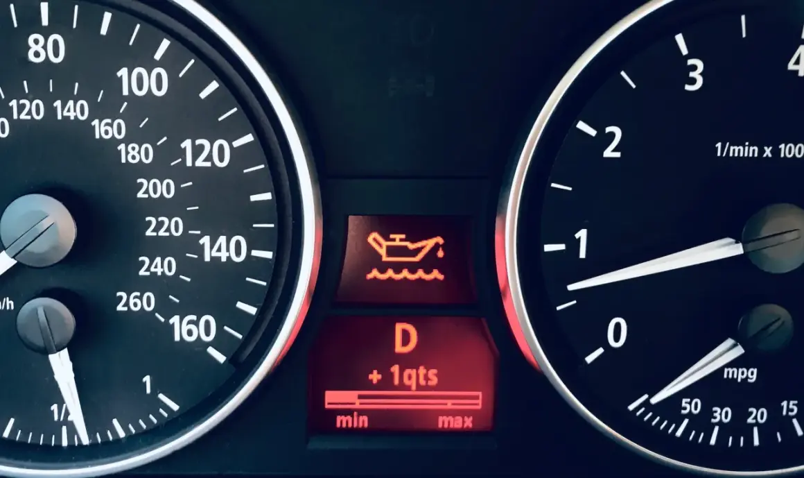 Tableau de bord d'une voiture avec le symbole vidange voiture allumé, indiquant un niveau d'huile bas.