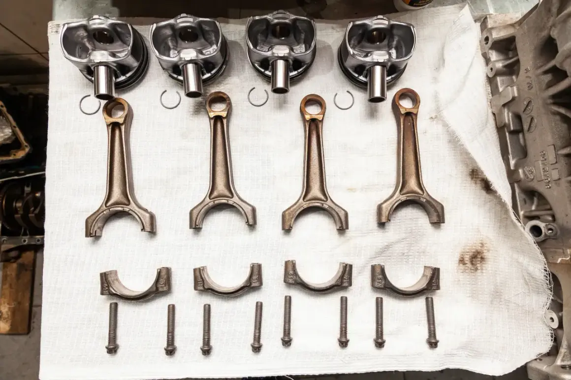 Pièces d'un moteur : pistons, bielles, chapeaux de bielle et vis. Prêt à réparer un moteur qui a eu un problème de couler une bielle.