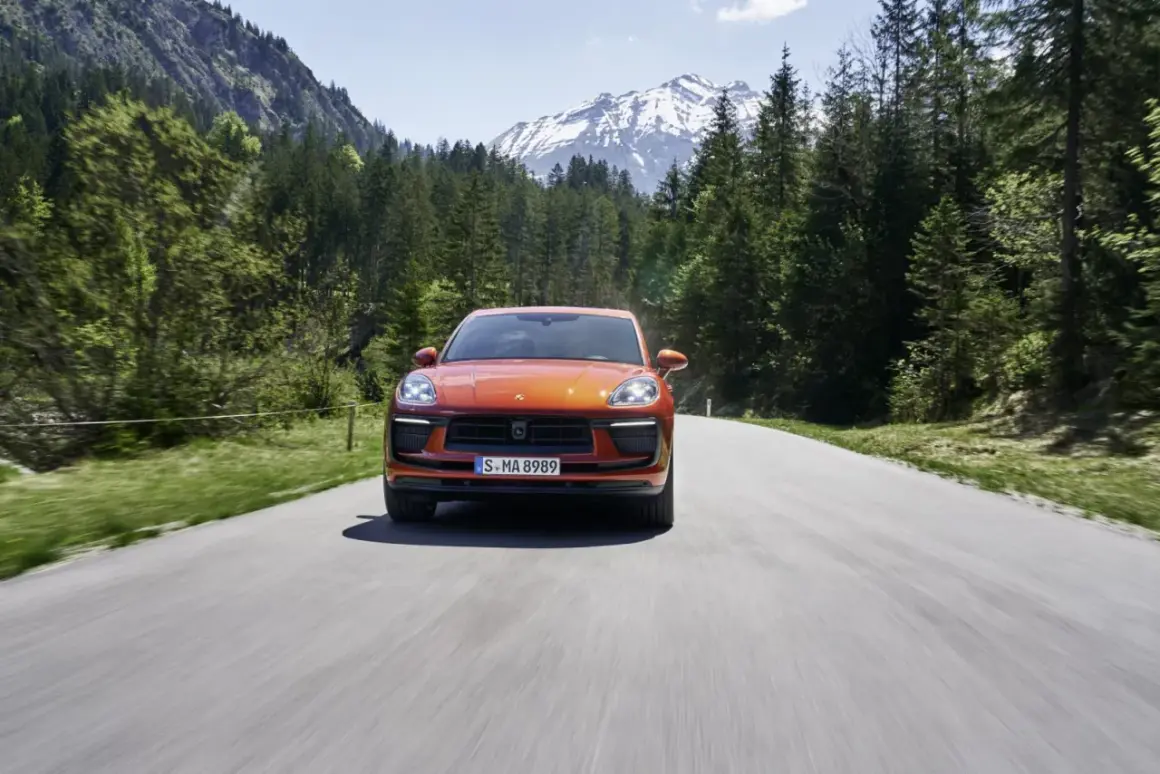 Porsche Macan orange sur une route de montagne, respectant la norme européenne d'émissions.