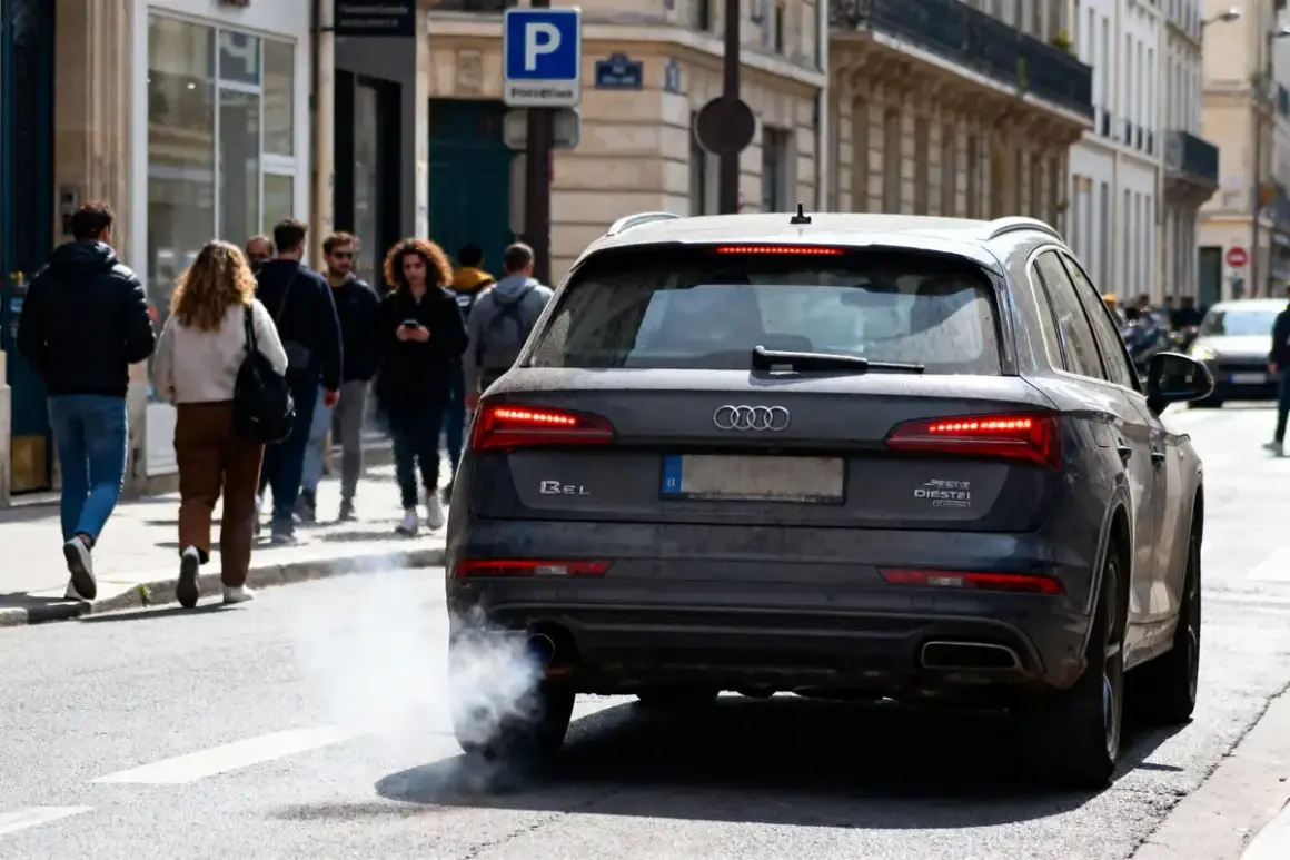 Une Audi émet une épaisse fumée blanche, signe d'une mauvaise odeur d'échappement diesel. Des passants marchent sur le trottoir.