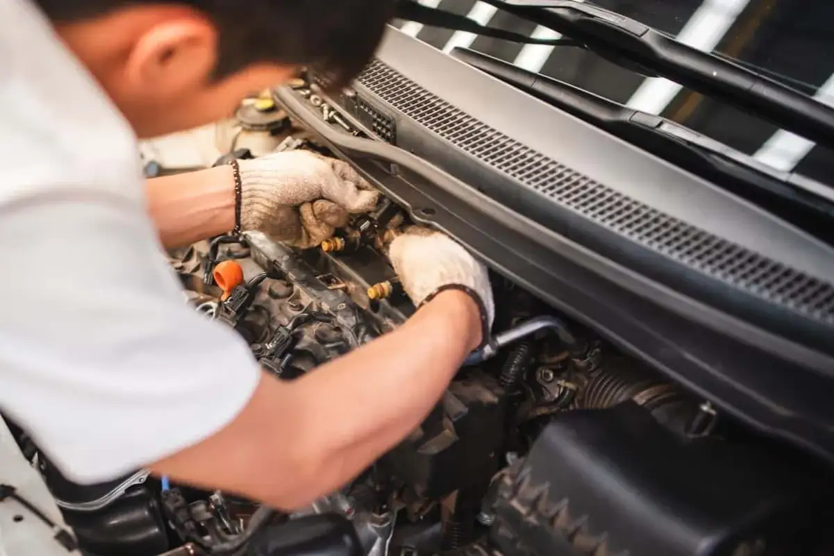 Mécanicien travaillant sur le moteur, peut-être pour résoudre le problème que ma voiture consomme trop d'essence.