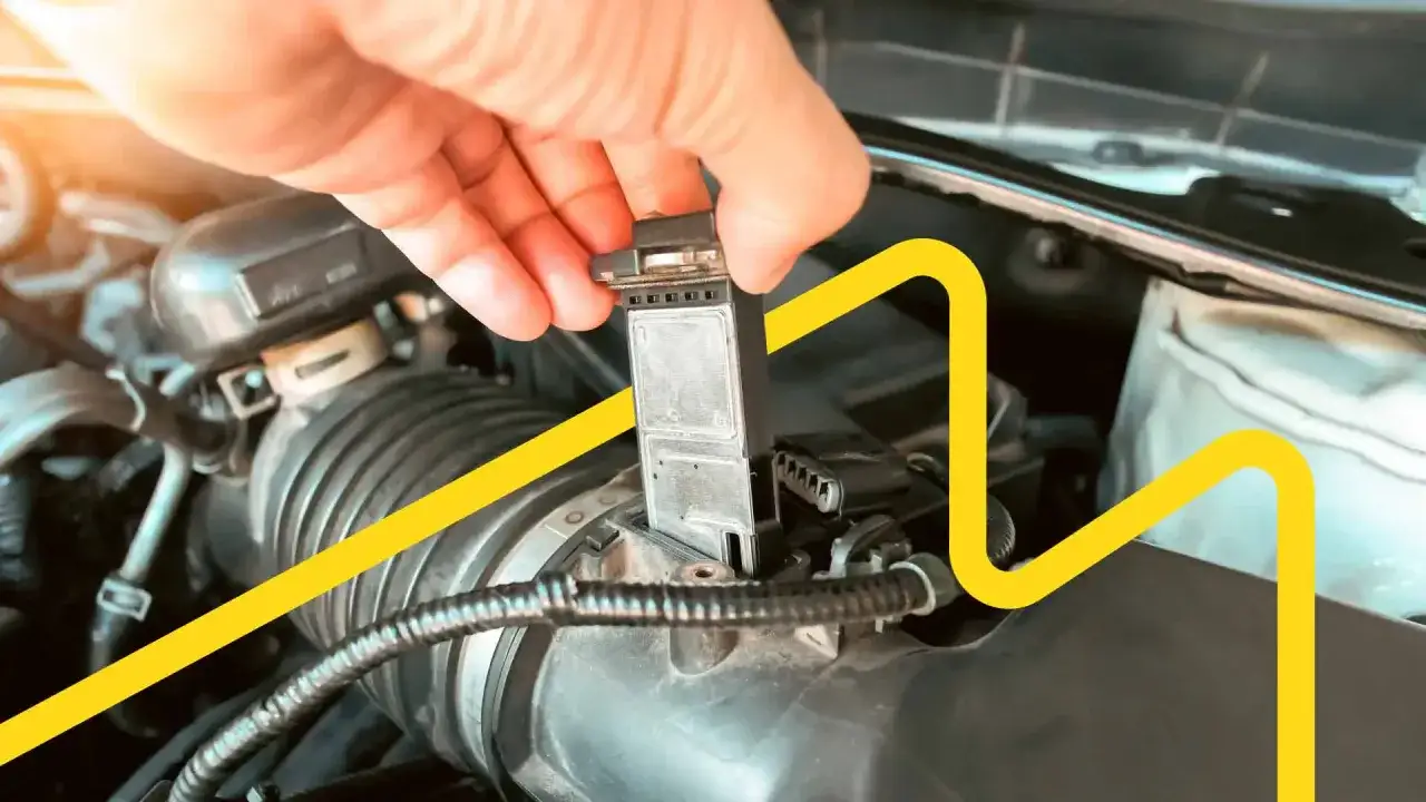Maintenant, vous savez comment nettoyer un débitmètre. Une main retire le composant du moteur de la voiture.